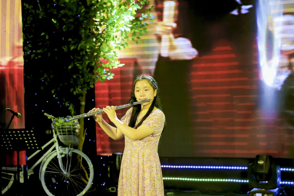 Học viên biểu diễn sáo ngang trên sân khấu trong hoạt động của HG Music