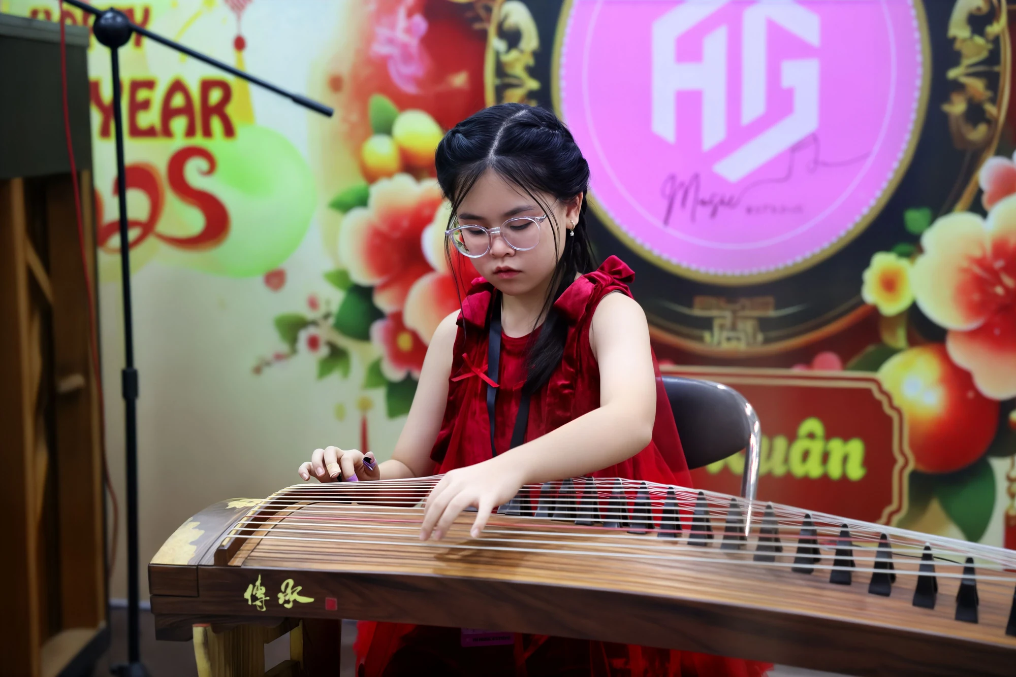 Người biểu diễn guzheng trước phông Sắc Xuân.