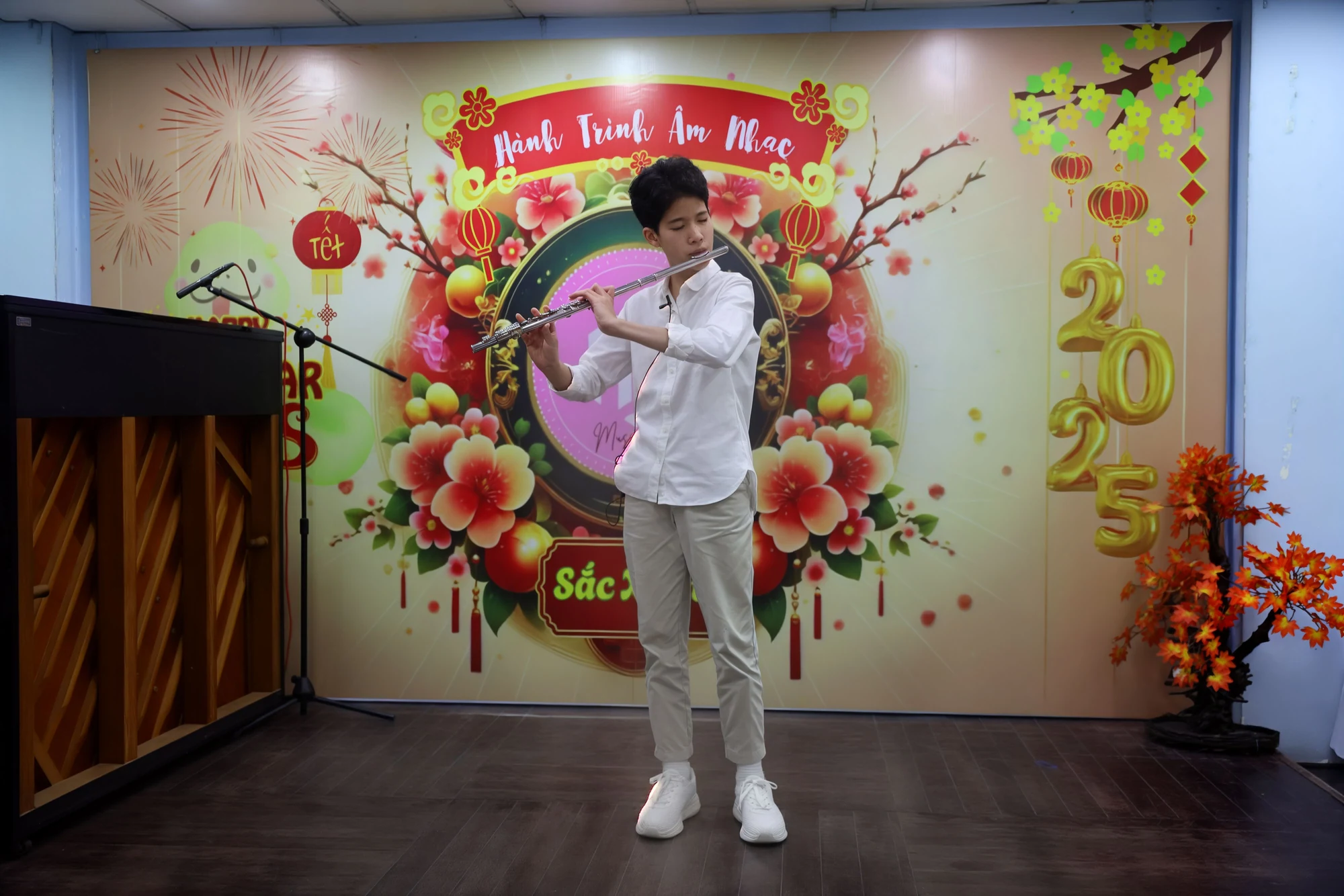 Người biểu diễn flute trước phông Sắc Xuân.