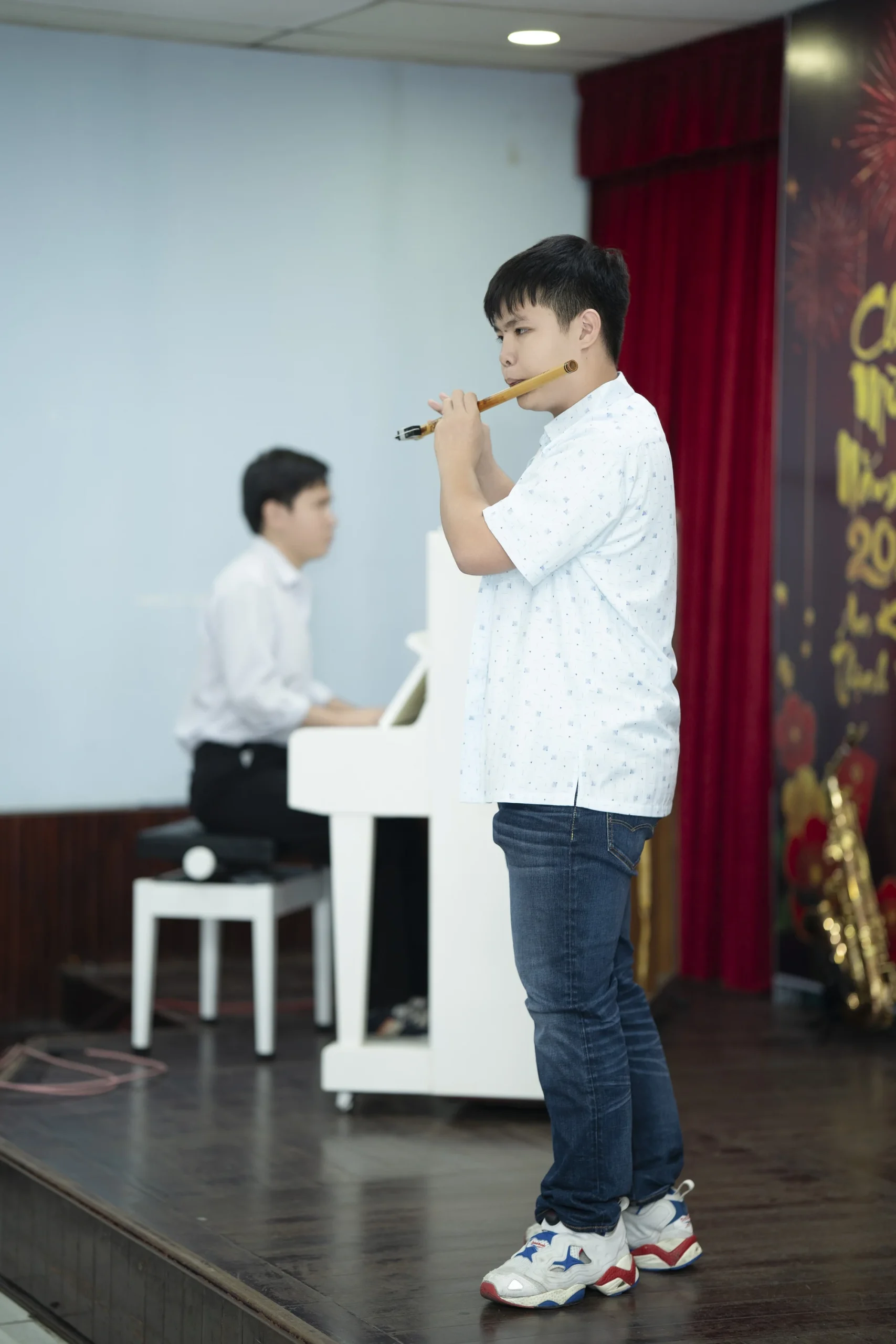 Người biểu diễn sáo trúc ở phía trước và người chơi piano trắng phía sau tại Giao Mùa.
